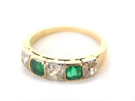 An emerald and diamond dress ring, with three old cut diamonds alternating with two square emeralds in a rub over setting, one diamond totalling 0.35ct two diamonds totalling 0.21ct and two square emeralds totalling 0.74ct, with tapered flat sized shank, 