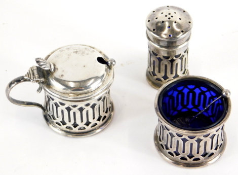 A George V silver cruet set, comprising mustard pot, with a thumb mould handle, 6cm high, open salt and pepper pot, with blue glass liners, Birmingham 1925, and associated spoon, 3.6oz all in.