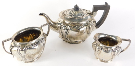 An Edward VII Art Nouveau three piece silver tea service, comprising teapot, two handled sugar bowl and milk jug, with angular handles, each repousse decorated with stylised scrolls, the teapot 19cm high, Chester 1909, 28oz all in. (3)