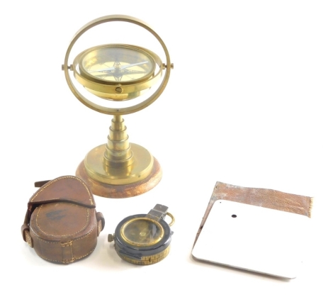 A 20thC brass table compass, 21cm high, a Verner's patent compass in leather case and a World War II heliograph plane spotting mirror in a leather case.