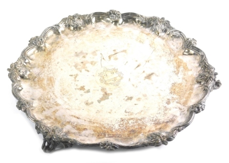 A 19thC silver plated salver, of large proportion, the pie crust edge with a scroll and flower head design, centred by a coat of arms on scroll feet, 45cm wide.