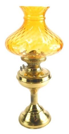 A 20thC brass oil lamp, with amber coloured glass shade, 52cm high.