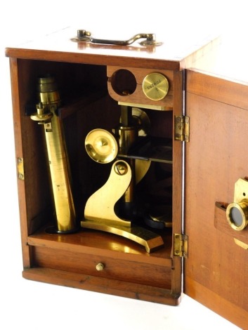 A 20thC brass microscope with elaborate stage and un-named lens, some pieces marked 3 powers, in mahogany case with swing handle, 29cm high.