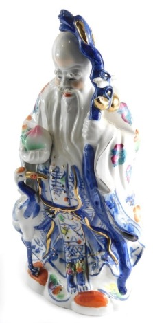 A 20thC Chinese pottery figure, of a bearded sage holding staff, predominantly in blue, orange, and green with gilt highlights, unmarked, 43cm high.