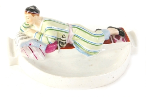 A 20thC Danko Russian porcelain ashtray, with a reclining figure to the back, polychrome decorated in pink, green, and blue, marked beneath, 22cm wide.