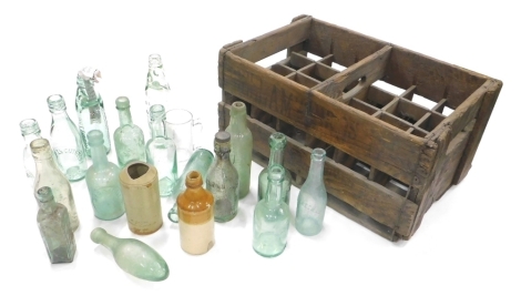 Various late 19th/early 20thC glass bottles, George Wells, 23cm high, various others Draper late Bayne with marble to the neck, John Davies, etc., contained in a bottle crate. (a quantity)