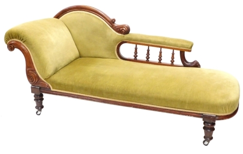 A late Victorian mahogany chaise lounge, upholstered in green fabric, on turned legs with later castors.