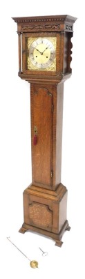 An oak grandmother clock, the hood with blind fret and dentil frieze above a brass stile flanked by cylindrical turned pillars, the trunk with an arched panel door, on bracket feet, 167cm high.