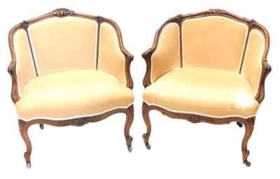 A pair of 19thC French mahogany show framed armchairs, upholstered in beige fabric on cabriole legs with castors.