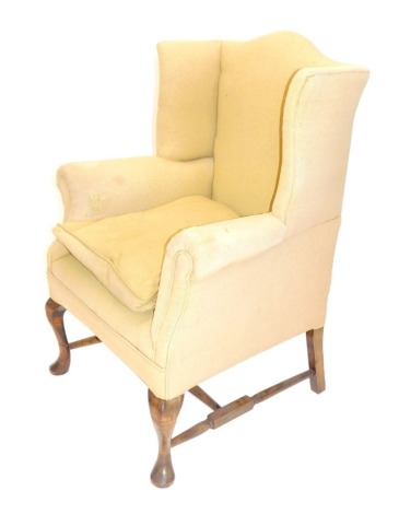 A George I style wing armchair, in yellow material on cabriole legs joined by a H stretcher.