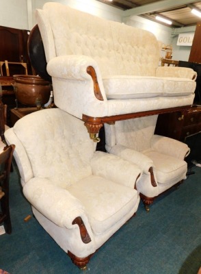 A walnut three piece suite, comprising two-seater sofa, and two armchairs, upholstered in gold pattern fabric with show frame on low with button feat, with brass castors, 88 wide. The upholstery in this lot does not comply with the 1988 (Fire & Fire Furni