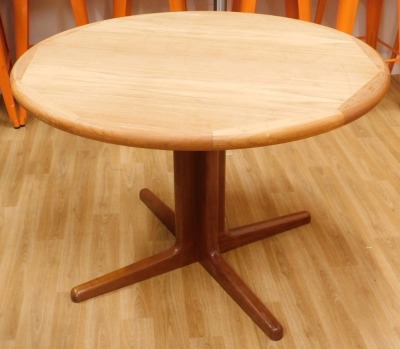 A Danish teak extending dining table, the circular top with shaped edge on a central column and tapering feet, one loose leaf, 107cm enclosed.