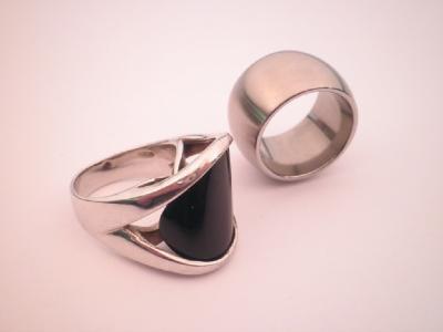 A large white metal barrel shaped ring together with a ring set with a