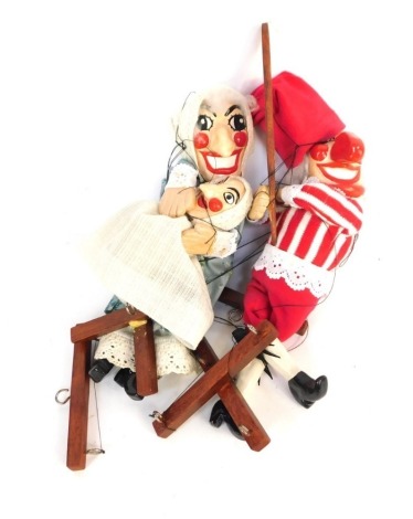 Two Punch & Judy puppets, She holding baby with wooden and cord attachments on large wooden stand.