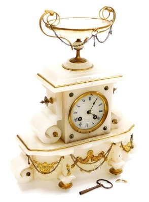 A late 19thC French gilt mounted alabaster mantel clock, the circular dial signed Ferlet Brenon with blue Roman numerals, the eight day movement with bell strike, the case surmounted by a tazza, on a serpentine base, with chain suspensions, raised on bra