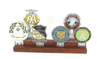 A car badge group, on two step plinth to include badges for AA, 589227, The Camping Club of Great Britain & Ireland, Road Safety Award, The Triumph Owners Club, Peterborough Motor Cycle Club and the Spalding & Tongue End Auto Club. 