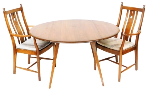 An Ercol dark elm drop leaf dining table, raised on square splayed legs, circa 1970, model number 382, 71cm high, 112cm wide, 63cm deep, 123cm extended, together with a pair of Ercol dark elm carver chairs, circa 1990, design 872A 'Stonor armchair'.