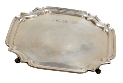 An Elizabeth II silver pie crust salver, raised on four scroll feet, monogram engraved to the front, verso presentation engraved, Viner's Limited, Sheffield 1957, 27½oz.