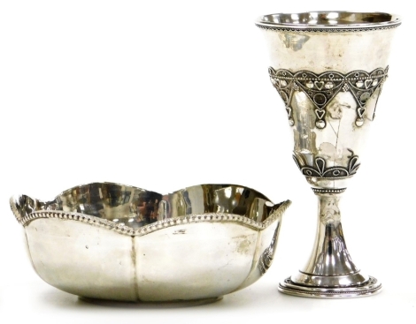 Two items of white metal, comprising goblet with tapering bowl, with reverse tapering stem on a circular base, with raised decoration of banding, hearts, dots, etc, 11.5cm high, and a small bowl with petalated rim and raised border, 12cm diameter.