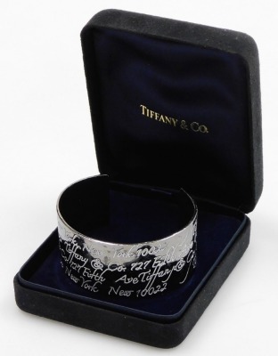 A cuff bangle, with white enamel engraved decoration, repeating '127 5th Avenue New York', and New York 122, stamped 1997 Tiffany & Co.925, boxed, 1.7oz