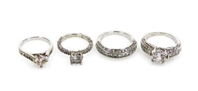 Four silver dress rings, each stone set, comprising three solitaire rings and a half hoop eternity ring, all boxed. (4)