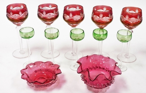 A set of five Continental ruby flash glass stemmed wine glasses, two cranberry glass dishes, and five stemmed green glass Schnapps glasses.