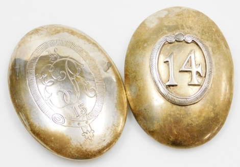 Two military white coloured metal buckles, of oval form, one engraved E.R 15, within a garter frame, the other applied with the number 14, within a scroll frame, 8cm high.