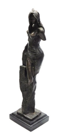 A bronze figure of a semi clad woman, verging on the rocks, raised on a rectangular black marble base, 38cm high.