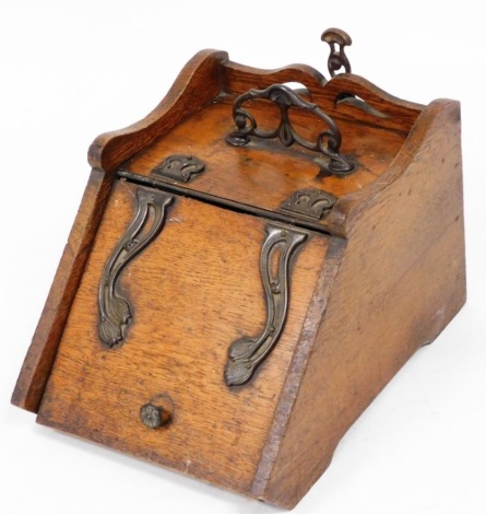 An early 20thC Art Nouveau style oak coal scuttle, with a raised back and side, floral cast metal pierced handle, Art Nouveau style mounts and floral handle, with scoop.