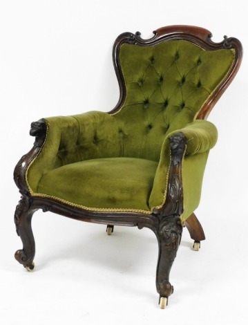 A Victorian rosewood shield back armchair, upholstered in green button back Draylon, the frame with foliate carving and eagle head arm terminals, raised on cabriole legs, brass capped on castors.