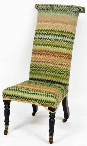 A Victorian mahogany prie dieu chair, upholstered in multi coloured wool work zigzag fabric, raised on turned legs, brass capped on castors.