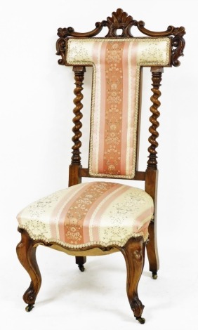 A Victorian walnut prie dieu chair, with foliate carving and bobbin turned back supports, overstuffed with striped floral upholstery, raised on cabriole legs, on castors.