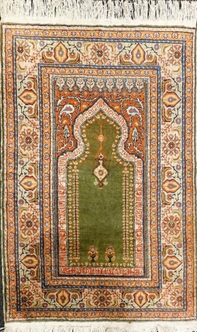 A Persian cream ground prayer rug, the green Mihrab, with hanging lantern and flowers, within foliate and floral borders, 139cm x 90cm.