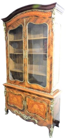 A Louis XV style kingwood bibliotheque, the domed top above a floral marquetry frieze, over a pair of glazed doors enclosing three shelves, above a double cupboard door base, the doors and sides with marquetry, inlaid with vases, putti and symbols of musi