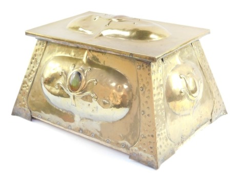 An Arts & Crafts brass coal box, with raised relief cartouche shields, Ruskin enamel and hammered with tapering sides, 30cm high, 48cm wide, 36cm deep.