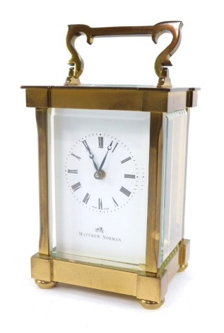 A Matthew Norman brass carriage clock, with white Roman numeric dial and retailer stamped Matthew Norman, the movement numbered 1754 and stamped Switzerland, with swing handle, 12cm high.