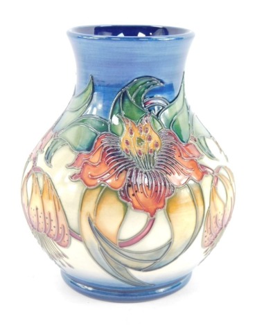 A Moorcroft vase, with passion fruit and flower detail on a blue and cream ground, with green Moorcroft stamp to underside and signed WM, 15cm high.