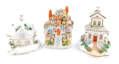 Three Staffordshire cottages, comprising a two story Staffordshire cottage with gilt decoration and floral clusters, 17cm high, a further smaller example, 15cm high, and a Staffordshire flat back cottage with orange chimneys, 18cm high. (3)