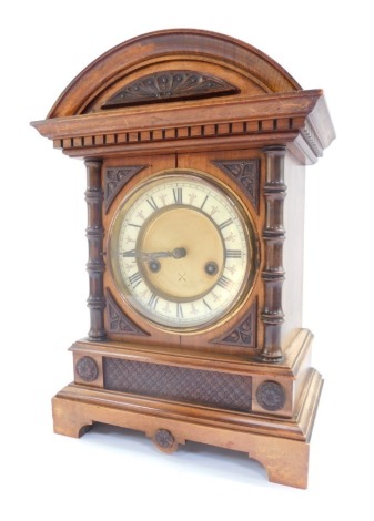 A late 19thC Hamburg American Clock Company oak cased mantel clock, circular brass dial with hour chapter ring, bearing Roman numerals, 14 day movement with coil strike, No 1077, the case of architectural form, with pendulum and key, 6cm high, 25cm wide.