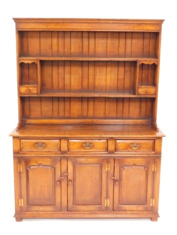 An oak dresser in 18thC style, the dresser top with two shelves and two drawers, above an arrangement of three drawers and three cupboard doors, on bun feet, 182cm high, 135cm wide, 45cm deep.