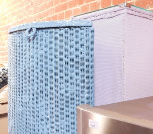 A blue Lloyd Loom corner linen basket, and a pink basket weave linen basket. (2)