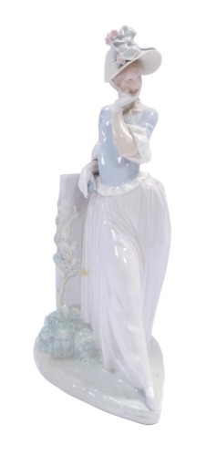 A Lladro porcelain figure, lady kneeling on rock in thoughtful pose, 38cm high.