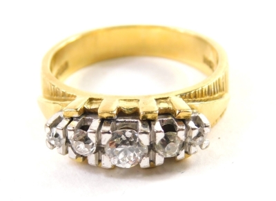 A dress ring, claw set with five graduated diamonds, probably in platinum, on an elaborate shank, yellow metal marked 18ct, size N.