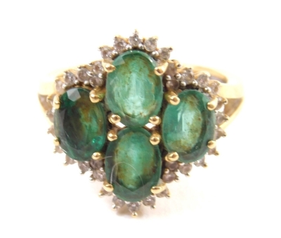 An 18ct gold dress ring, claw set with four central green stones surrounded by small diamonds on a part pierced shank, size N-O, 4.8g all in.