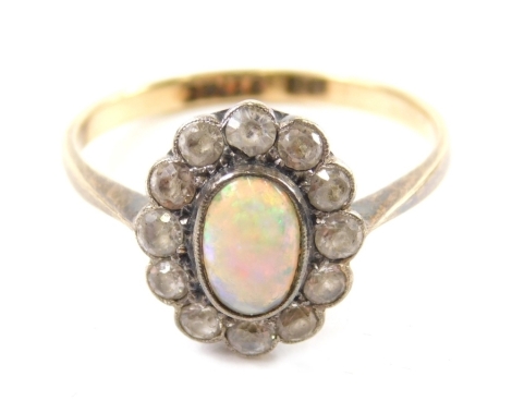 A 9ct gold and silver opal dress ring, the oval stone surrounded by small white stones, size N, 2g all in.