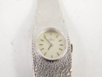 A 9ct white gold lady's Omega cocktail watch, the 1cm wide oval face with baton numerals and pointers, with textured bracelet marked .375, 29g all in. - 2