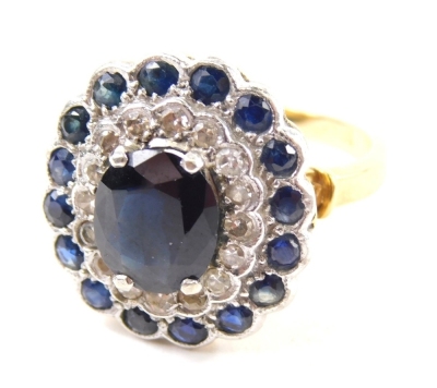 An 18ct diamond and sapphire dress ring, with a stepped floral setting on pierced shank, claw set with a central oval stone, size N-O, 6.3g all in.