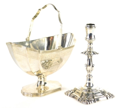 A George III silver basket, with strap work swing handle, shaped body, vacant shield cartouche, inverted stem on shaped foot, maker Henry Chawner, London 1791, 14cm wide, 5.7oz, and a weighted George I style candle stick, unmarked. (2)