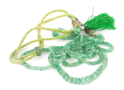 A Middle Eastern jade necklace, the two strand faceted jade beaded necklace, with a green and gilt thread, adjustable necklace strand, with tassel end, 102cm long overall, 30.3g all in.