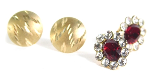 A pair of earrings, centred with oval red stones, surrounded by small white studs, with two further studs in one case.